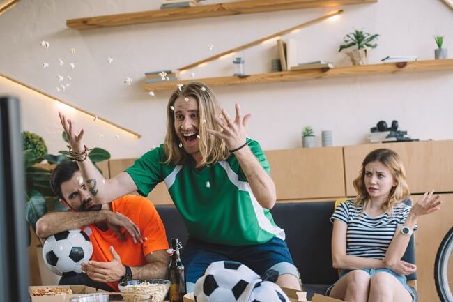 Man excited watching TV but his friends are not